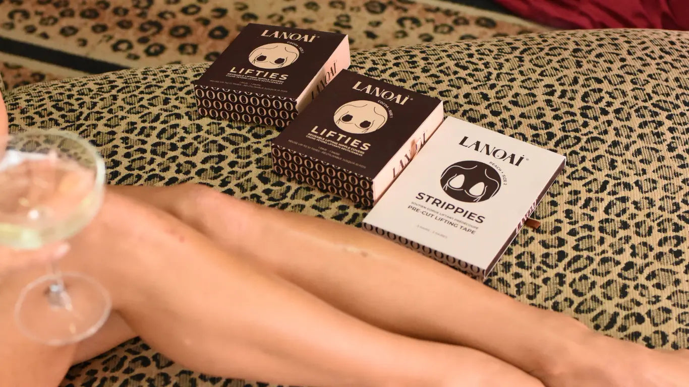 Lanoai lifting bra alternative boob tape products on a leopard print surface with a hand holding a glass of wine.